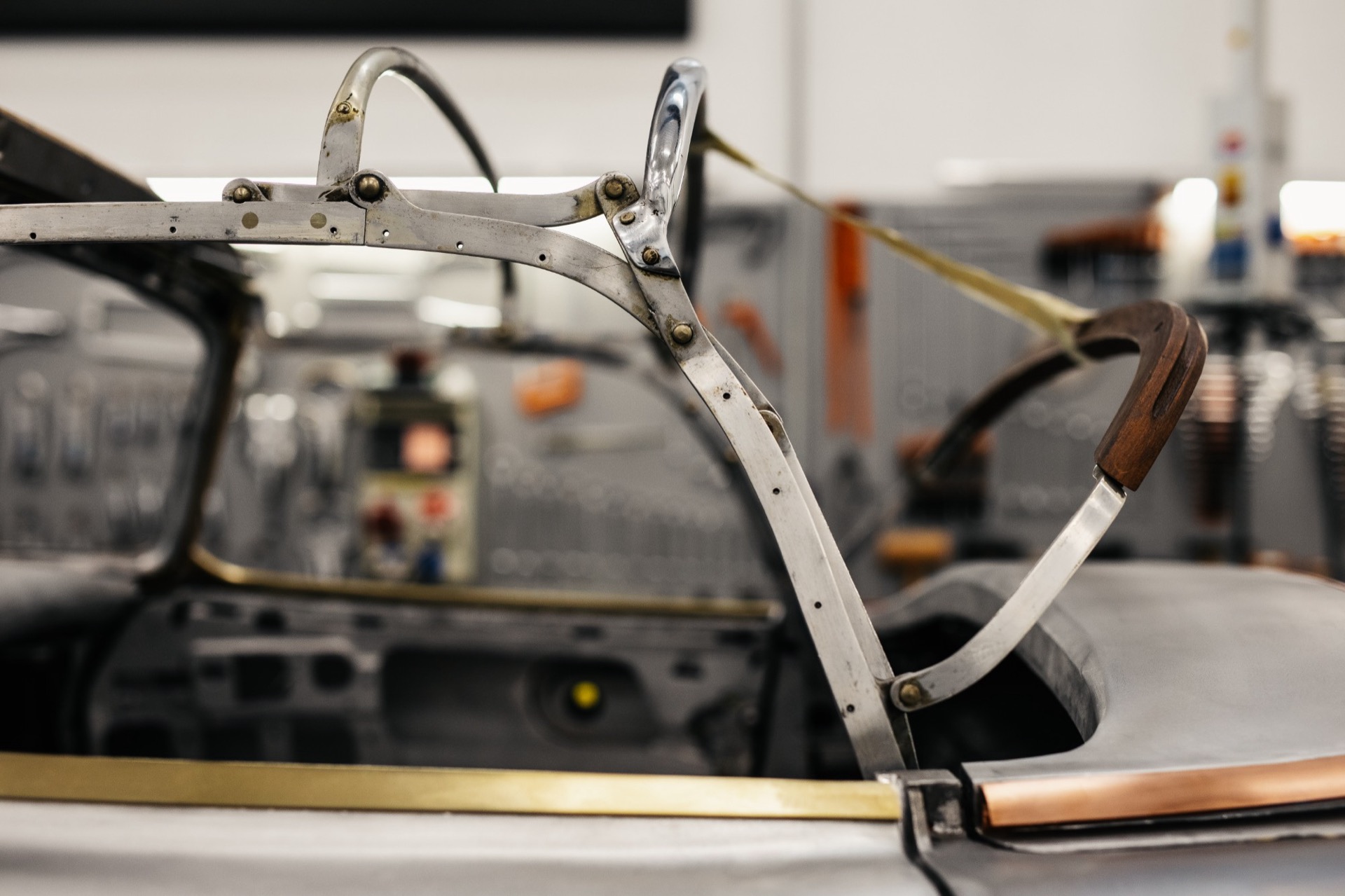 Close-up of the folding soft-top mechanism of a 300 SL Roadster with wooden handle and brass trim