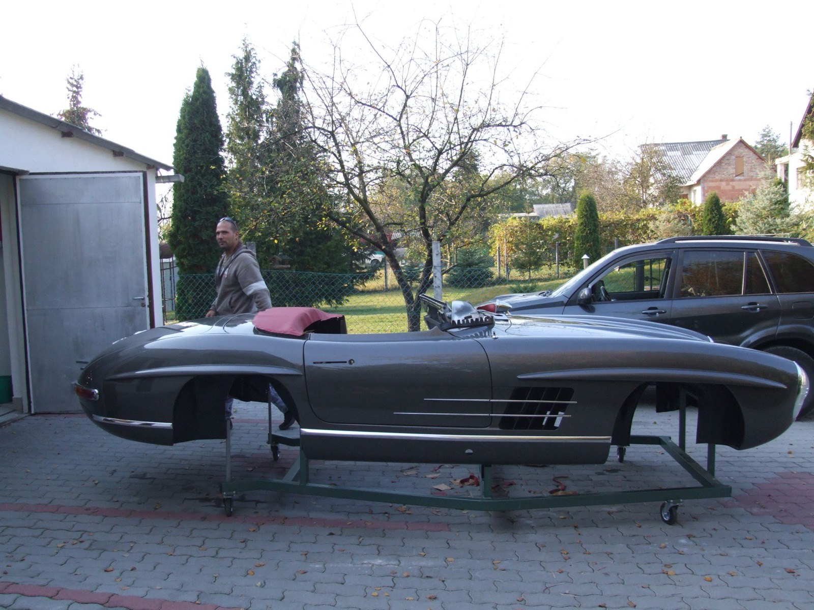 The painted body of the 300 SL Roadster on a rolling frame in front of the old garage