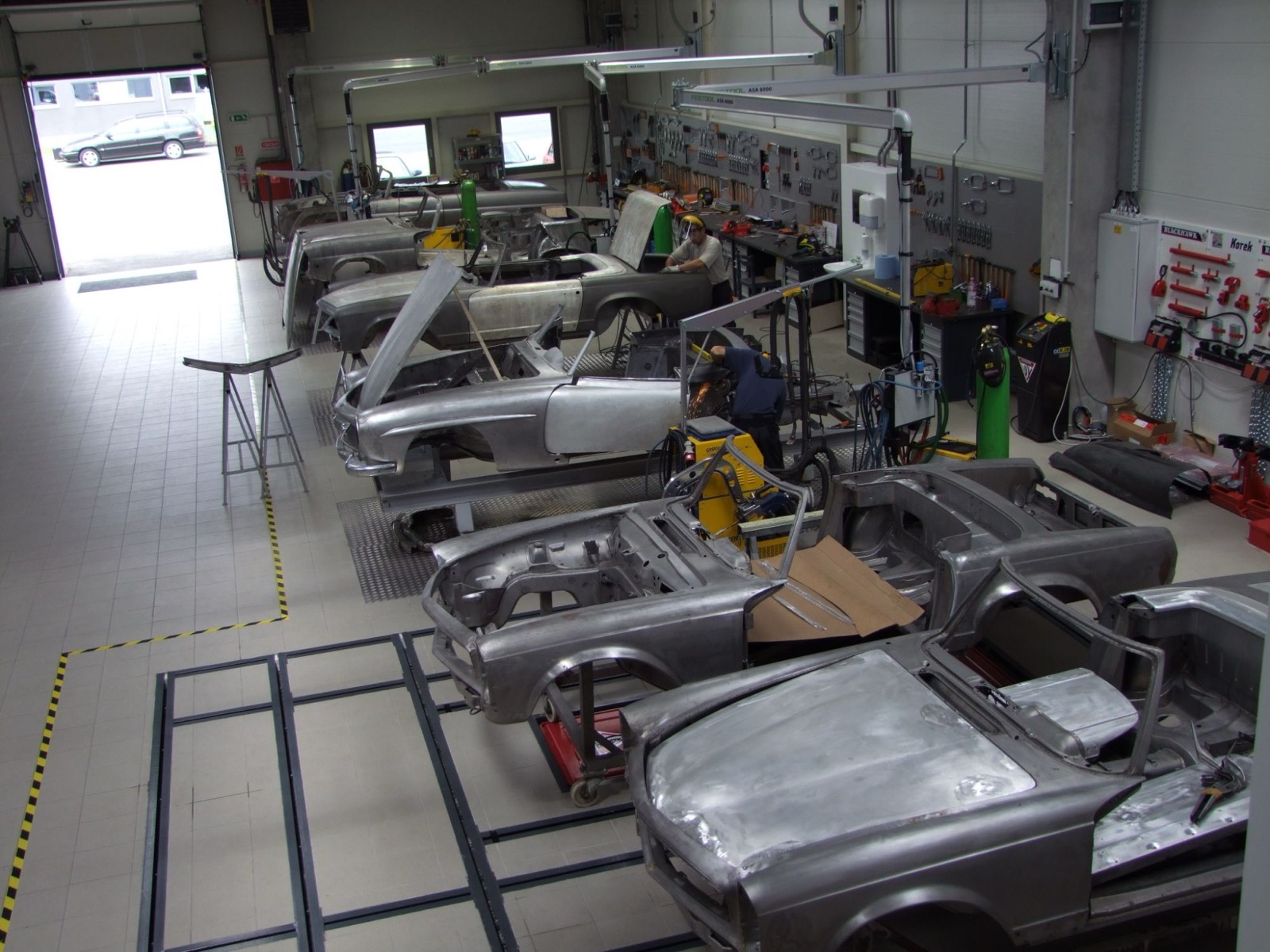 Several bare-metal Mercedes-Benz SL bodies in restoration in the bodywork bay
