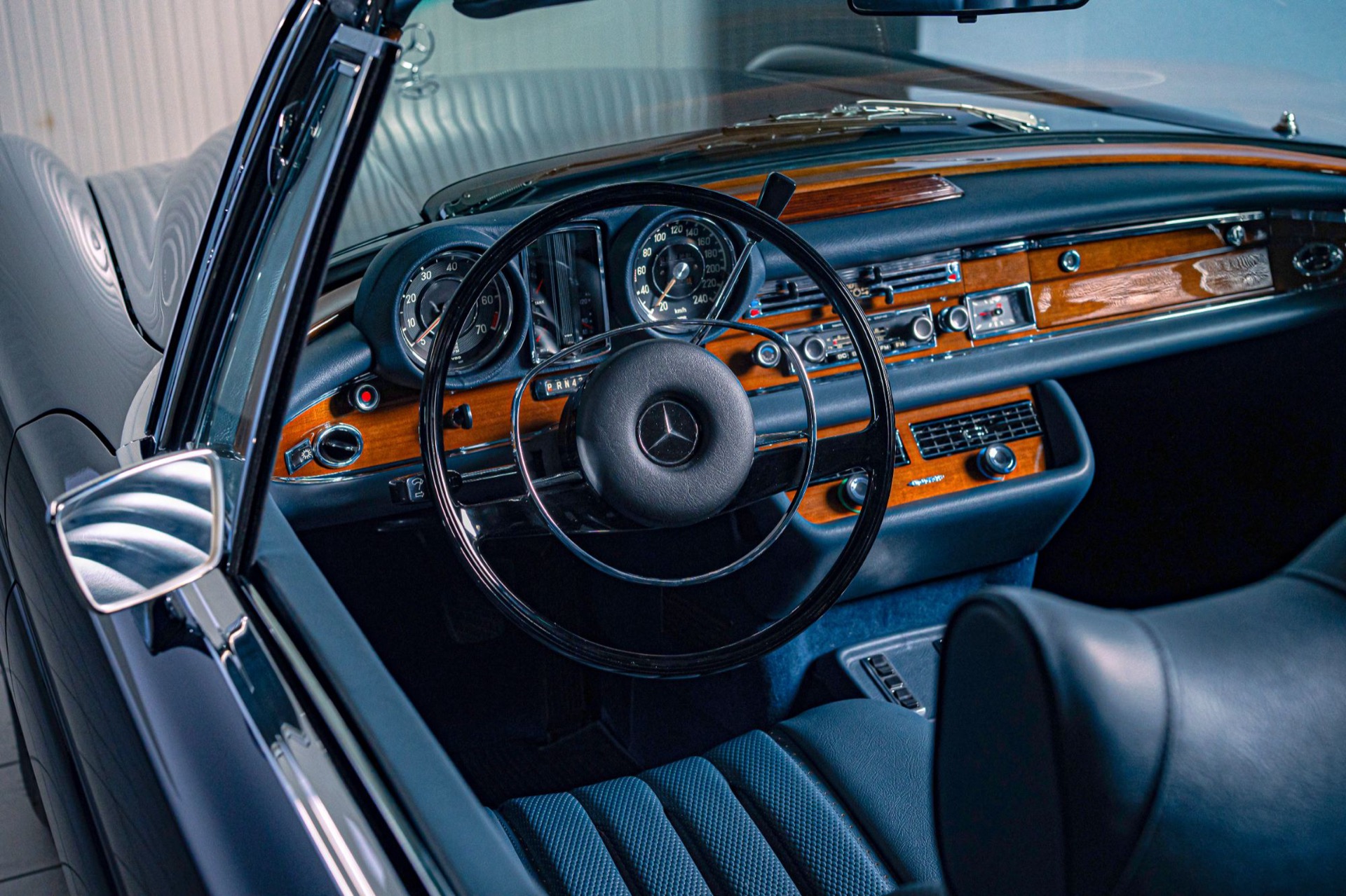 Wooden dashboard, steering wheel and blue leather seats of a restored W111 convertible